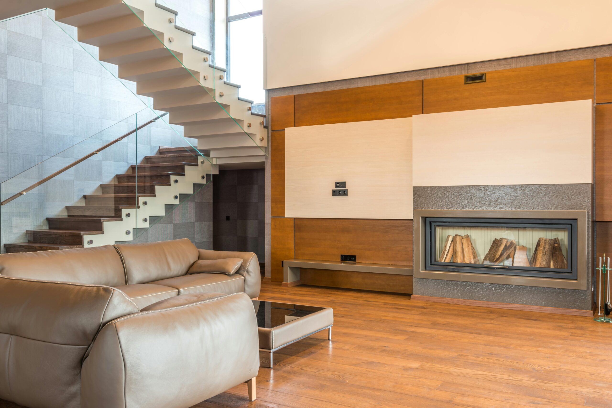 Modern living room featuring a minimalist design with a sleek staircase and comfortable leather sofa.